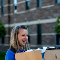An Alumna carrying a student's box.